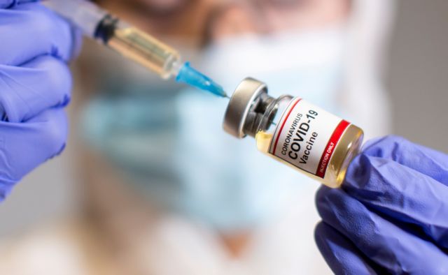 FILE PHOTO: A woman holds a small bottle labeled with a "Coronavirus COVID 19 Vaccine" sticker and a medical syringe in this illustration